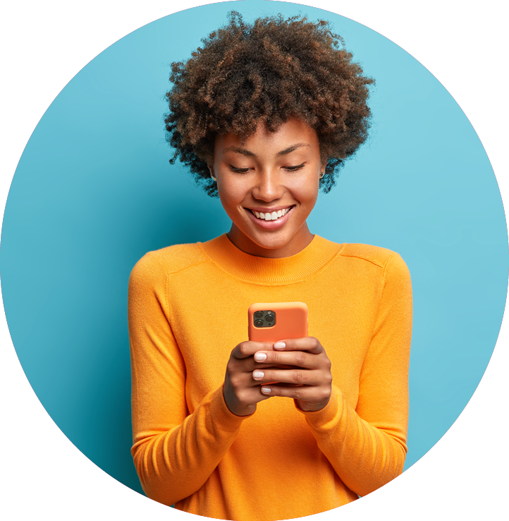 Online lifestyle concept  Cheerful good looking woman with Afro hair sends text messages via mobile phone dressed casually searches gifts for holiday in internet uses smartphone app browses webpage